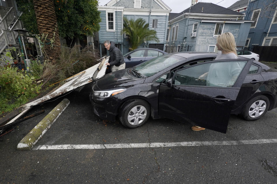 Bart Mehlhop, left, lifts a fence blown over on to Kelly Logue's car, by a storm that swept through Sacramento, Calif., overnight, Wednesday, Jan. 27, 2021. (AP Photo/Rich Pedroncelli)