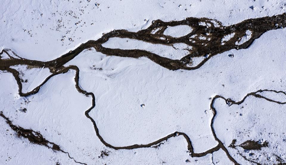 A stream flows through a snowy landscape.