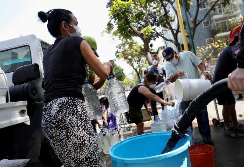 FILE PHOTO: People collect water on a street in Caracas during the coronavirus pandemic