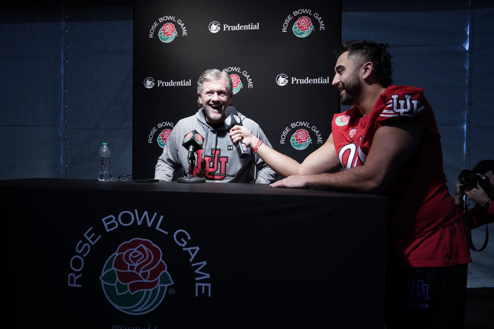 Utah head coach Kyle Whittingham, left, smiles as he is interview by Utah defensive tackle Devin Kaufusi during media day ahead of the Rose Bowl NCAA college football game Saturday, Dec. 31, 2022, in Pasadena, Calif. (AP Photo/Marcio Jose Sanchez)