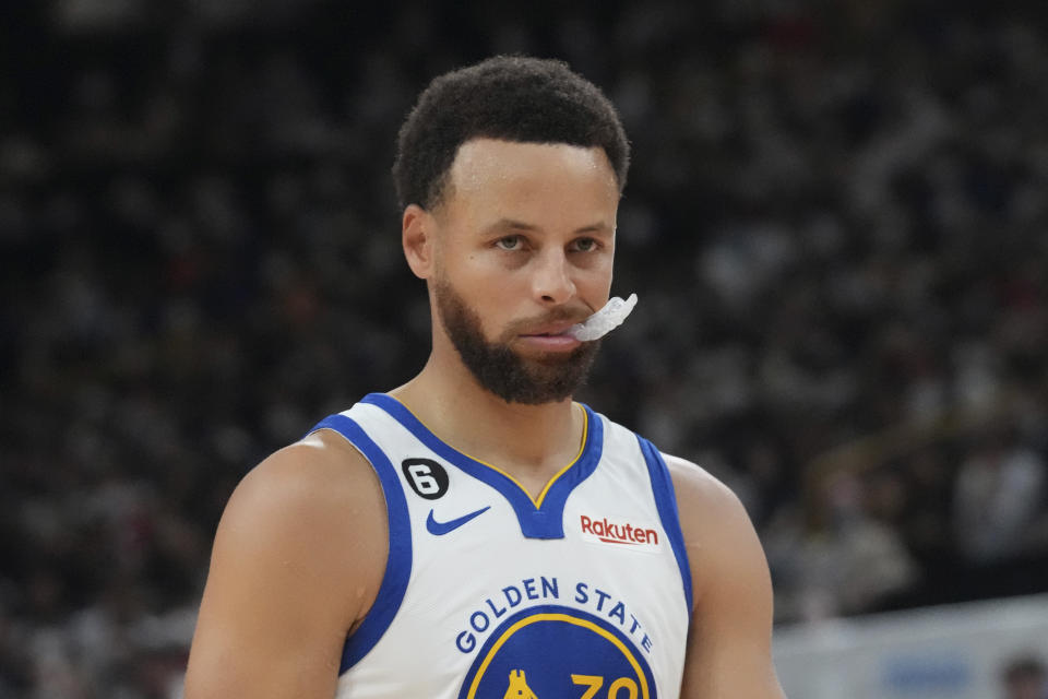 Golden State Warriors' Stephen Curry bites his mouth guard prior to the start of his preseason NBA basketball game against Washington Wizards, Friday, Sept. 30, 2022, at Saitama Super Arena, in Saitama, north of Tokyo. (AP Photo/Eugene Hoshiko)