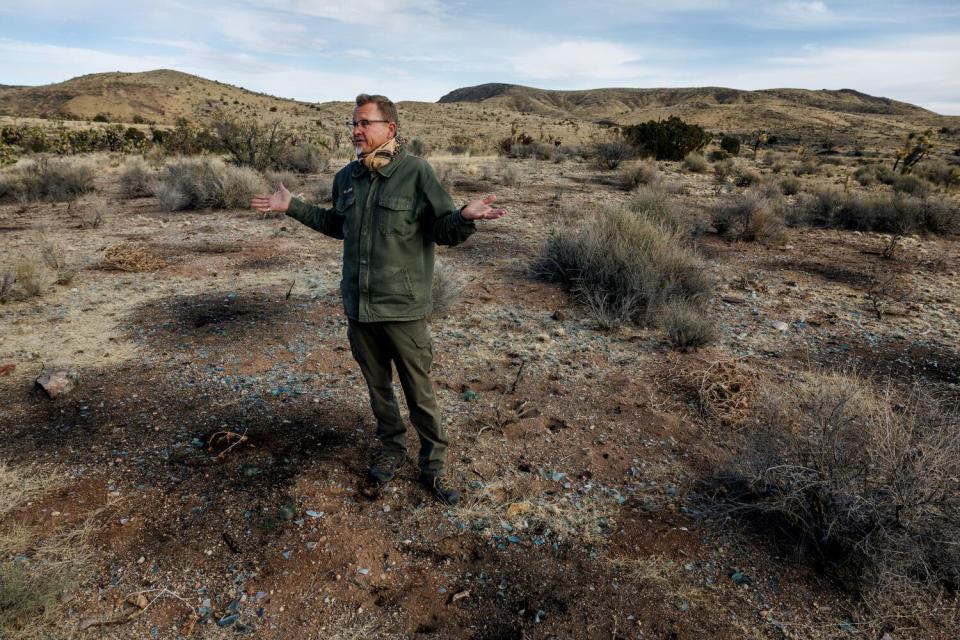 A man talks and gestures in the desert.