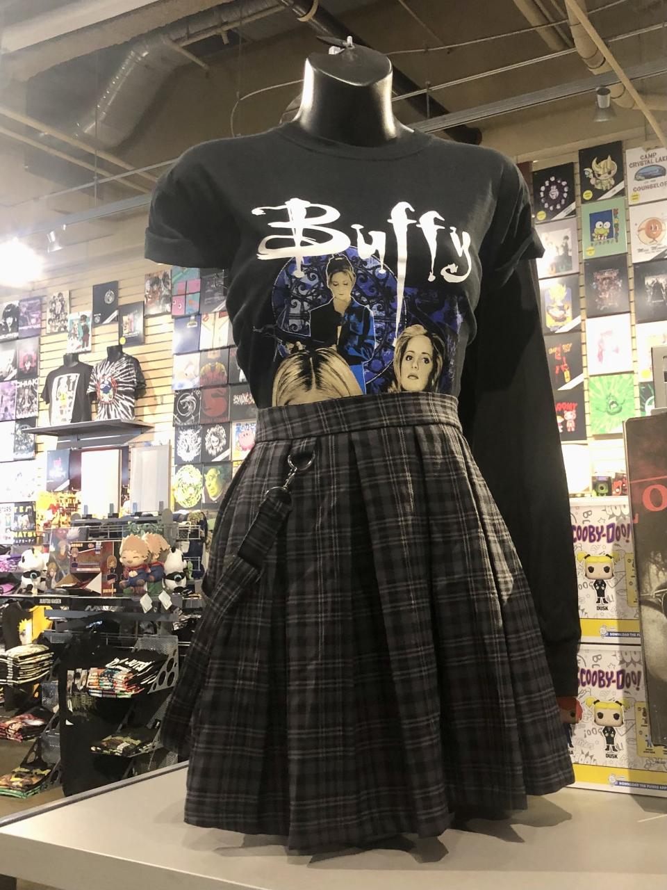 "Buffy The Vampire Slayer" shirt tucked into a dark plaid skirt on display