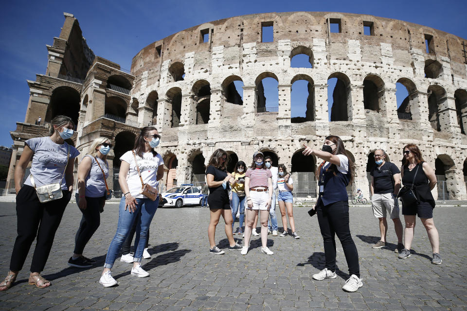 Tourists wear face masks to curb the spread of COVID-19 as they listen to a tour guide outside the ancient Colosseum, in Rome, Friday, May 21, 2021. The easing of travel restrictions this week have favored travel and tourism. (Cecilia Fabiano/LaPresse via AP)