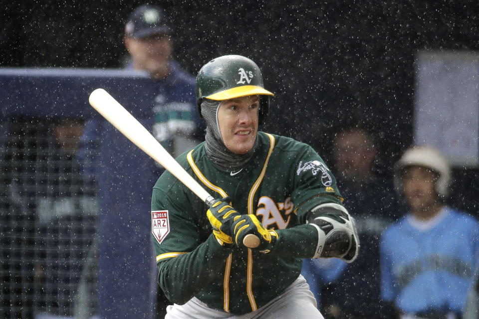 Oakland Athletics' Mark Canha waits in the rain for a pitch during the first inning of a spring training baseball game against the Seattle Mariners, Friday, Feb. 22, 2019, in Peoria, Ariz. (AP Photo/Charlie Riedel)