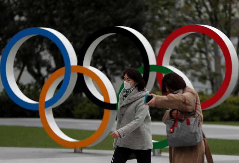 Passersby wearing protective face masks, following an outbreak of the coronavirus disease, walk past the Olympic rings in front of the Japan Olympics Museum, in Tokyo