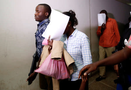 Gladys Kaari and Oliver Muthee, cover their faces as they are escorted from the Mililani Law Courts where they appeared as suspects in connection with the attack at the DusitD2 complex, in Nairobi, Kenya January 18, 2019. REUTERS/Thomas Mukoya
