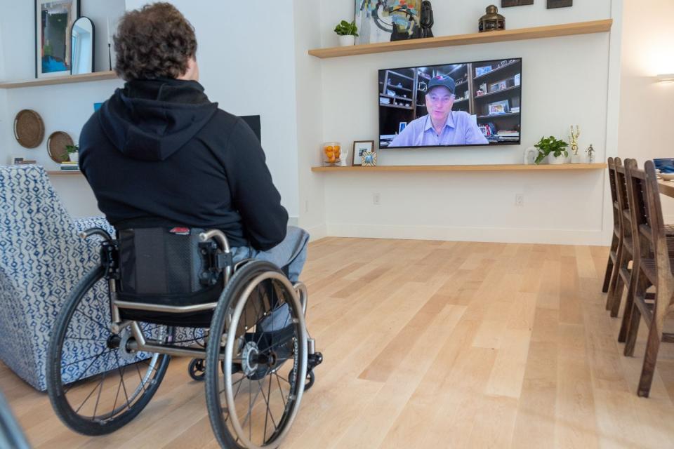 Retired Air Force Staff Sgt. Brian Schiefer watches a pre-recorded message from actor and humanitarian Gary Sinise, whose foundation provided Schiefer with the specially adapted home.