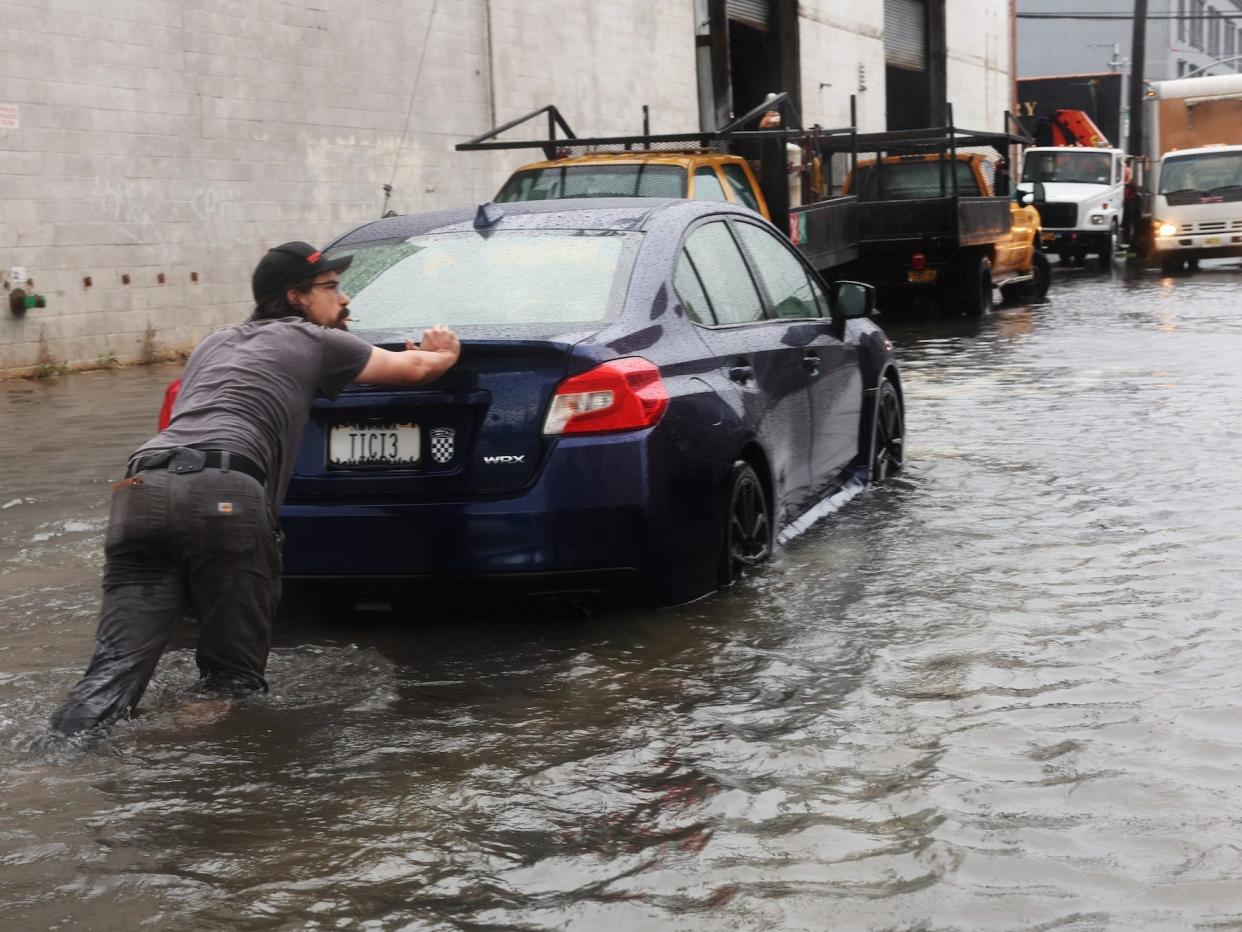 A man pushes a car through the flooded streets of Red Hook in Brooklyn.