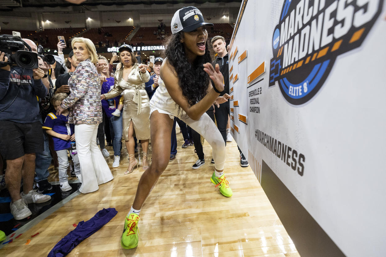 Angel Reese slaps LSU's nameplate on the Final Four bracket with coach Kim Mulkey smiling in the background after the Tigers beat the Miami Hurricanes on March 26, 2023, in Greenville, South Carolina. (AP Photo/Mic Smith)