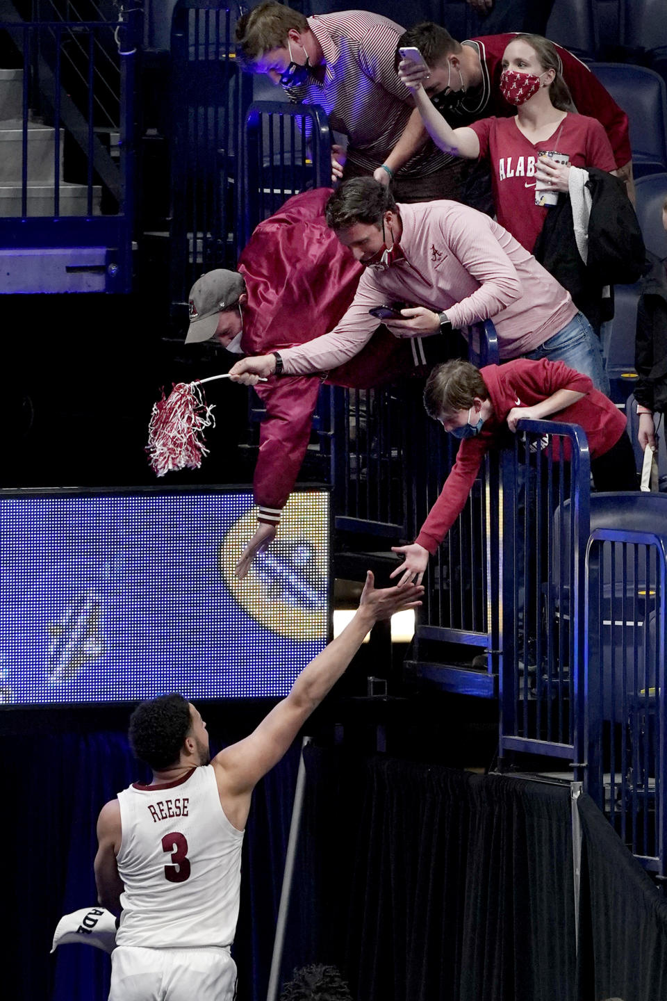 Alabama's Alex Reese (3) jumps up to slap hands with fans as he leaves the court after Alabama beat Tennessee in an NCAA college basketball game in the Southeastern Conference Tournament Saturday, March 13, 2021, in Nashville, Tenn. (AP Photo/Mark Humphrey)