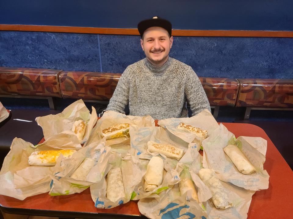lucien posing with all the burritos from taco bell in front of him