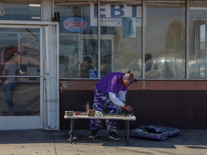 Vincent Hubbard leans over a folding table to make a chess move outside a Louisiana Fried Chicken.