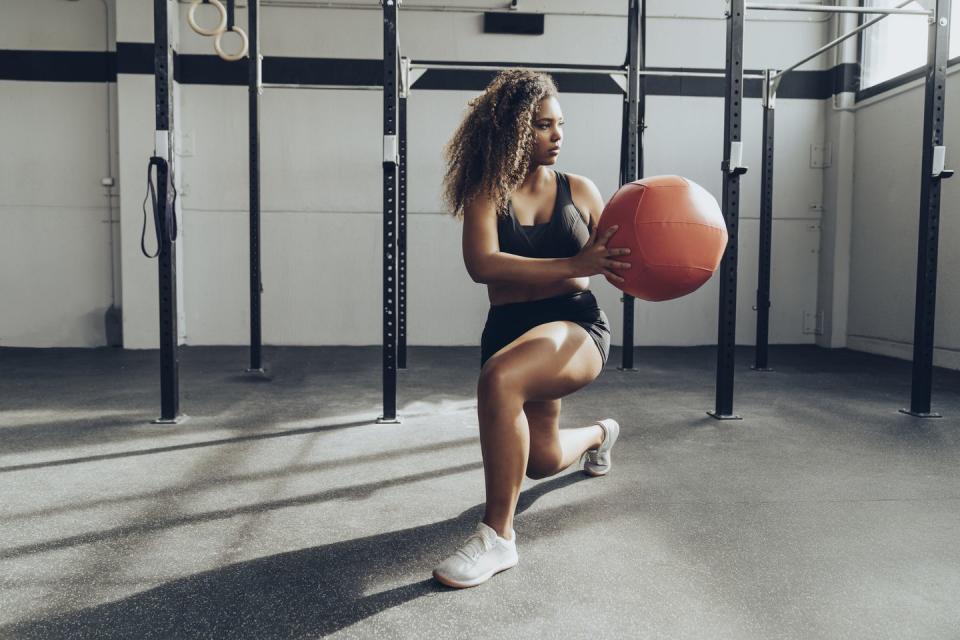 young woman exercising with medicine ball in gym