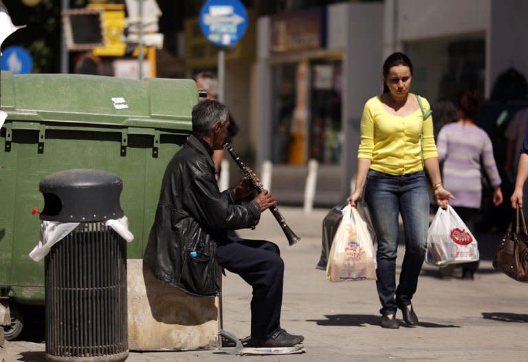 A woman carrying shopping bags walks past a man playing the clarinette on Nicosia's Ledra street on March 20, 2013. Debt-hit Cyprus scrambled on Wednesday to draw up a Plan B to secure an EU bailout after MPs rejected an unprecedented bank deposit levy, while also seeking to limit the amount of money leaving the island