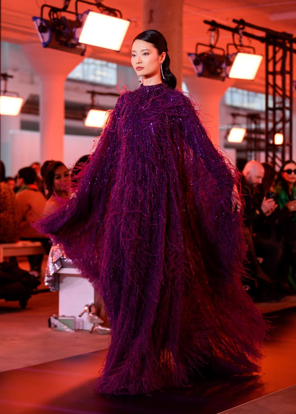 A model walks the runway in a sparkling purple feathered caftan at the Pamella Roland fall/winter 2024 show during New York Fashion Week on Feb. 12, 2024.