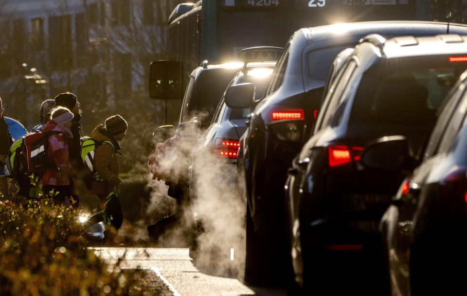 FILE - Cars give off exhaust fumes as children head to school in Frankfurt, Germany, on Monday, Feb. 27, 2023. The European Union has been at the forefront of the fight against climate change and the protection of nature for years, but it now finds itself under pressure from within to pause new environmental efforts amid fears they will hurt the economy. The first sign was earlier this year when Germany, the bloc's economic giant, delayed a deal to ban new internal combustion engines in the EU by 2035 amid ideological divisions inside the German government. (AP Photo/Michael Probst, File)