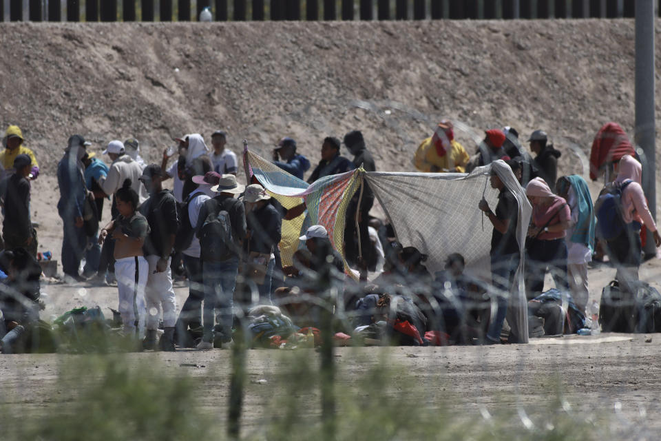 Migrants wait for U.S. authorities, between a barbed-wire barrier and the border fence at the US-Mexico border, as seen from Ciudad Juarez, Mexico, Wednesday, May 10, 2023. The U.S. on May 11 will begin denying asylum to migrants who show up at the U.S.-Mexico border without first applying online or seeking protection in a country they passed through, according to a new rule released on May 10. (AP Photo/Christian Chavez)