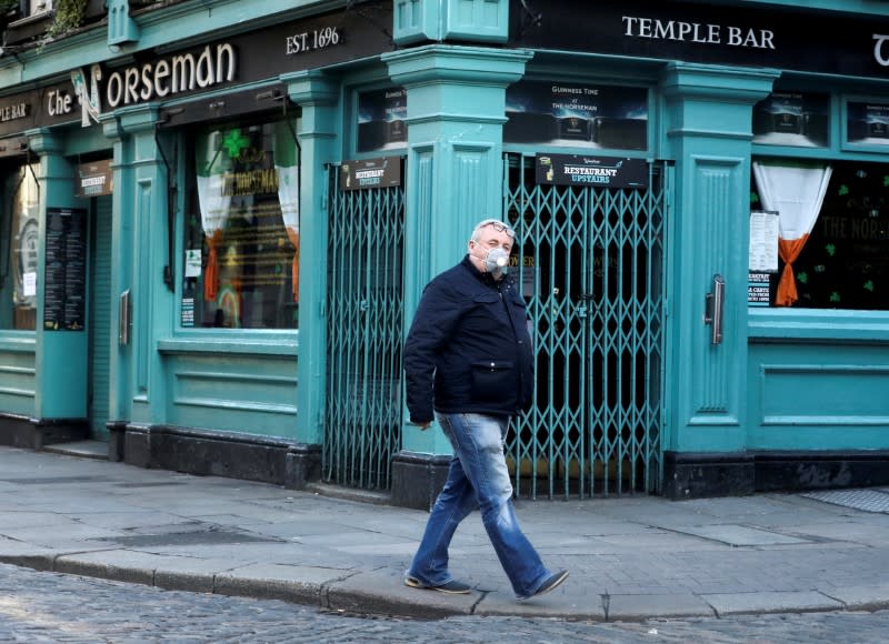 FILE PHOTO: A man wearing a protective face mask passes The Norseman pub, as bars across Ireland are to close voluntarily to curb the spread of coronavirus in Dublin