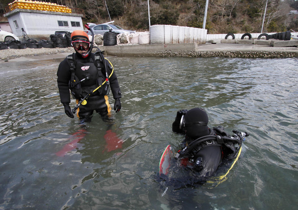 In this Sunday, March 9, 2014 photo, Yasuo Takamatsu, left, listens to his instructor Masayoshi Takahashi before taking a diving lesson at Takenoura bay, Miyagi prefecture, northern Japan. Nearly three years after the earthquake and tsunami disaster that struck Japan's northern pacific coastline, Takamatsu is learning to scuba dive in hopes of finding his wife. As Japan marks the third anniversary of the 2011 tsunami Tuesday, 2,636 people remain missing, their bodies presumably swept out to sea. Another 15,884 have been confirmed dead. (AP Photo/Koji Ueda)