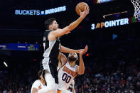 San Antonio Spurs forward Doug McDermott, left, drives past Phoenix Suns center JaVale McGee (00) during the first half of an NBA basketball game Monday, Dec. 6, 2021, in Phoenix. (AP Photo/Ross D. Franklin)