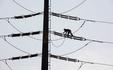 An employee of K-Electric fixes cables on a power transmission tower in Karachi, Pakistan, August 22, 2016. REUTERS/Akhtar Soomro