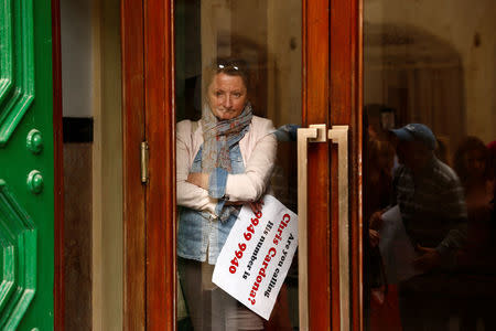 A civil society activist looks out from inside the Valletta police station as a formal complaint was made with the police, demanding questioning of Maltese Economy Minister Chris Cardona, after some of the journalists from the Daphne Project initiative reported him as having met with one of the men accused of the murder of anti-corruption journalist Daphne Caruana Galizia, in Valletta, Malta April 19, 2018. REUTERS/Darrin Zammit Lupi