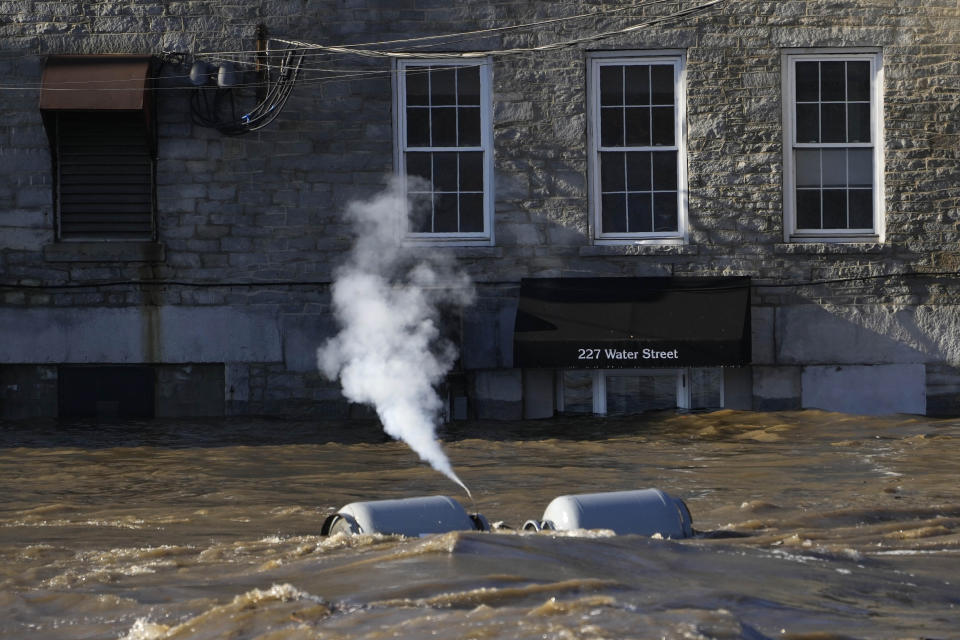 Propane tanks set free by flood waters discharge gas as they float on the Kennebec River through Augusta, Maine, Tuesday, Dec. 19, 2023. Waters continue to rise in the river following Monday's severe storm. (AP Photo/Robert F. Bukaty)