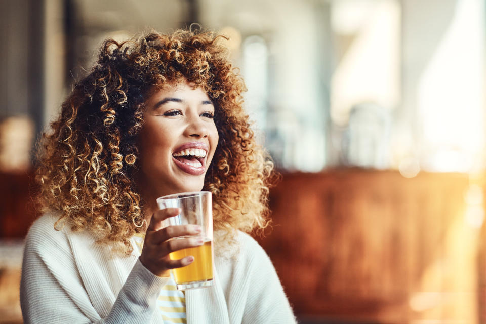 A woman holds her drink while chatting at a bar