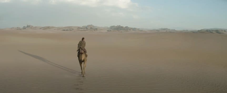 Obi-Wan riding an animal in the desert