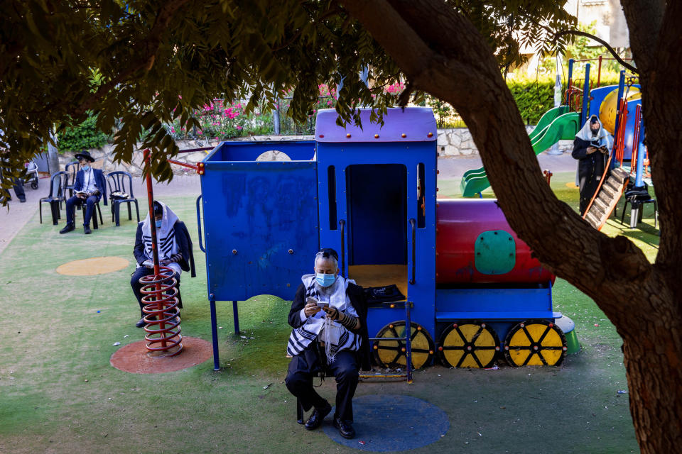 Ultra-Orthodox Jews pray at a playground next to their homes as they wear protective face masks help curb the spread of the COVID-19 coronavirus in Bnei Brak, Israel, Thursday, July 2, 2020. Israeli ministers have approved additional measures and special coronavirus Cabinet will meet Thursday to discuss further restrictions as the daily infection rate in the country neared 1,000. (AP Photo/Oded Balilty)