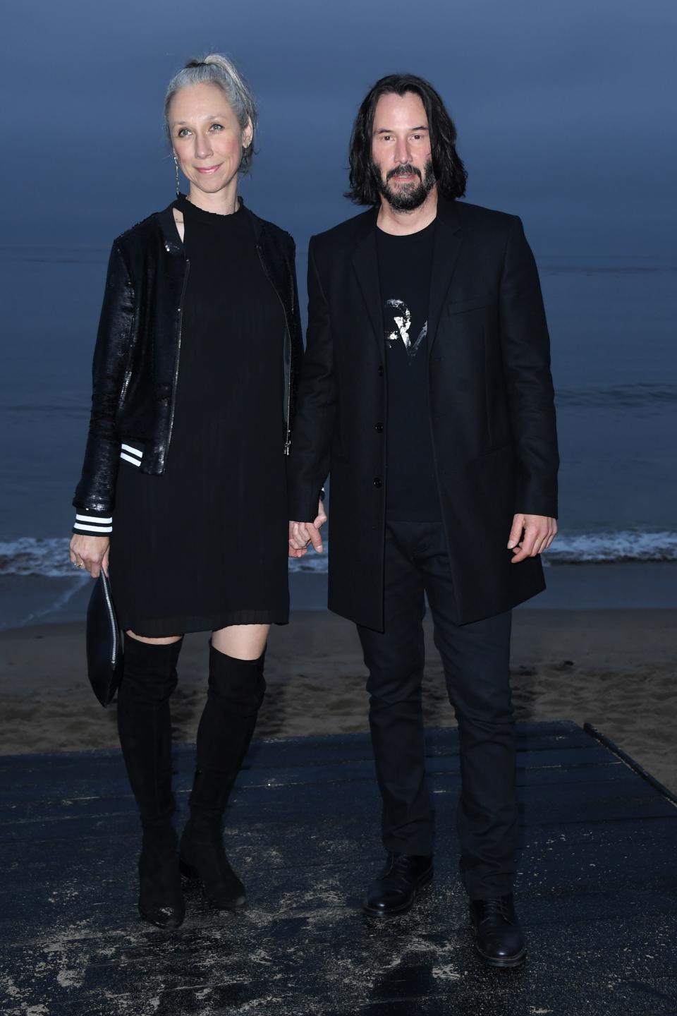 A photo of Keanu Reeves and Alexandra Grant holding hands at the Saint Laurent Mens Spring Summer '20 Show in June 2019 in Malibu.