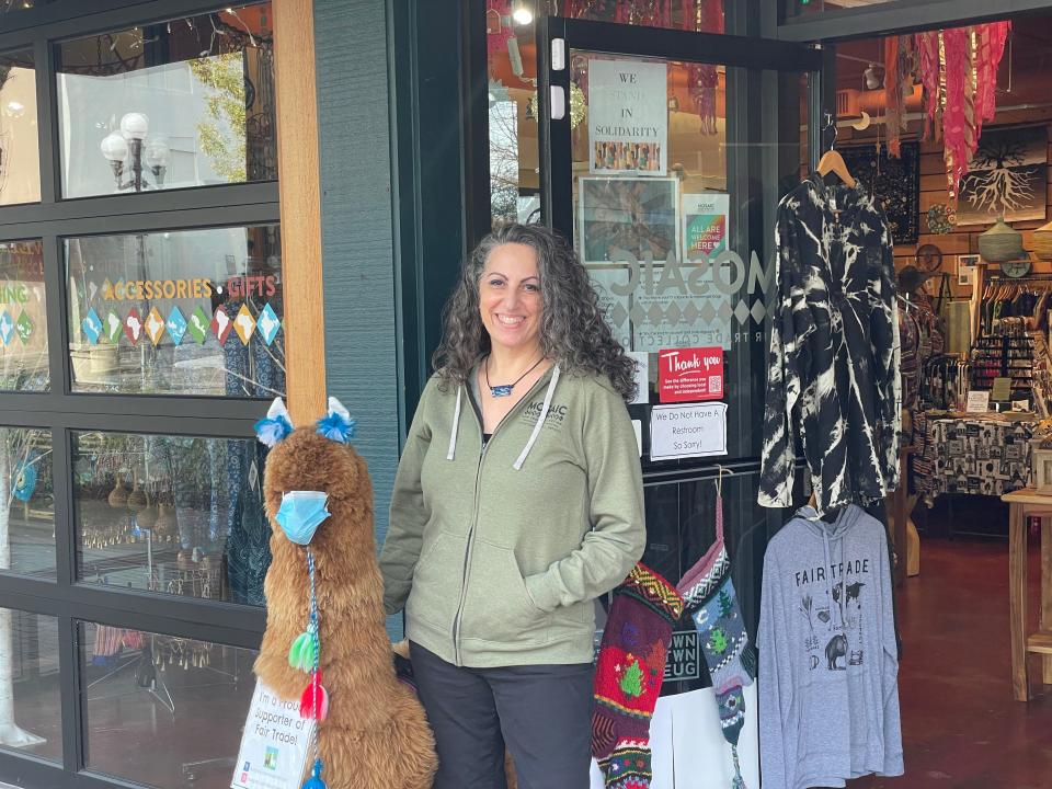 Mosaic Fair Trade Collection owner Liisa John stands with a masked llama outside her store in downtown Eugene.