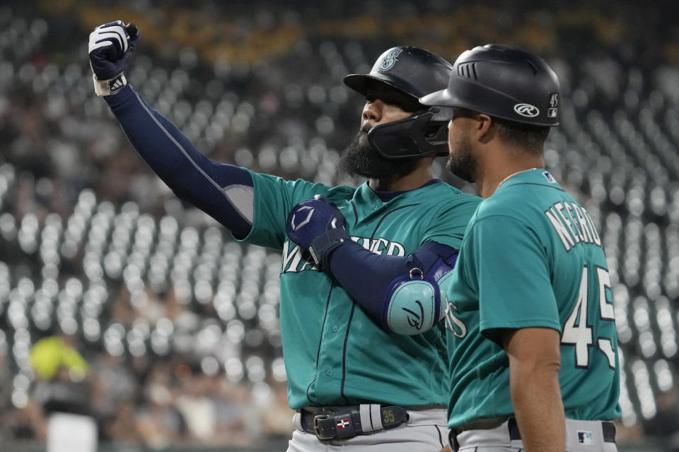 Seattle Mariners' Teoscar Hernandez, left, reacts after hitting a two-run single as first base coach Kristopher Negrón looks on during the sixth inning of a baseball game against the Chicago White Sox in Chicago, Monday, Aug. 21, 2023. (AP Photo/Nam Y. Huh)