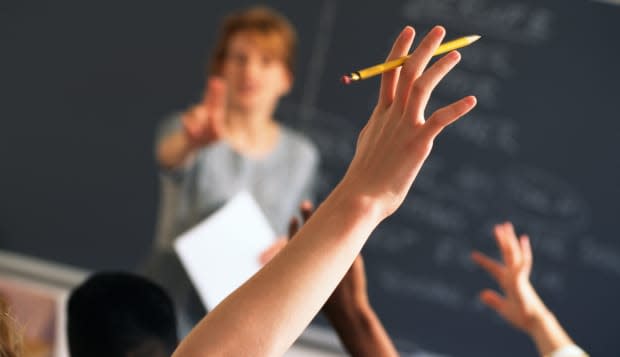 Teacher pointing to raised hands in classroom