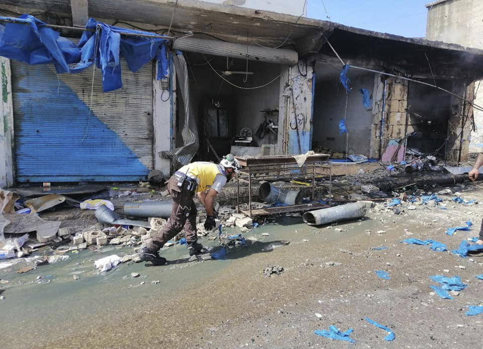 This photo provided by the Syrian Civil Defense White Helmets, which has been authenticated based on its contents and other AP reporting, shows a civil defense worker, works in front of damaged shops after shelling hit a street in the town of Ehssem, southern Idlib, Syria, Friday, May 3, 2019. Syrian state media and activists are reporting a wave of government and Russian airstrikes, including indiscriminate barrel bombs, on the rebel-held enclave in northwestern Syria where a seven-month truce is teetering under a violent escalation. (Syrian Civil Defense White Helmets via AP)