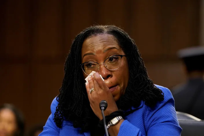 Judge Ketanji Brown Jackson wipes away tears as she listens to Senator Cory Booker. 