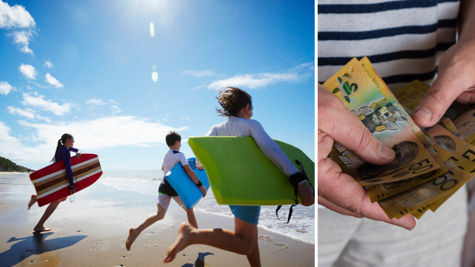 Three kids run towards the ocean on a sunny day holding boogie boards and a person holds $50 notes.