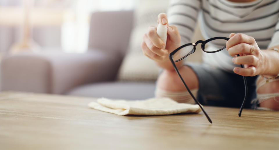 Cropped shot of an unrecognizable woman cleaning her reading glasses at home