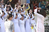 Former U.S. first lady Michelle Obama and female students at the Can Giuoc high school hold their arms in heart shapes as they say goodbye in Long An province, Vietnam, Monday, Dec. 9, 2019. Mrs. Obama is on a visit to Vietnam to promote education for adolescent girls. (AP Photo/Hau Dinh)