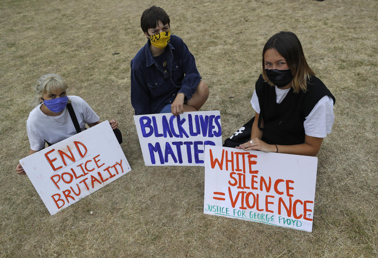 Protesters hold up placards as people gather for a demonstration on Wednesday, June 3, 2020, in Hyde Park, London, over the death of George Floyd, a black man who died after being restrained by Minneapolis police officers on May 25. Protests have taken place across America and internationally, after a white Minneapolis police officer pressed his knee against Floyd's neck while the handcuffed black man called out that he couldn't breathe. The officer, Derek Chauvin, has been fired and charged with murder. (AP Photo/Kirsty Wigglesworth)