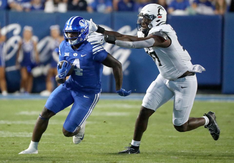 Brigham Young Cougars running back Miles Davis (4) runs past Cincinnati Bearcats defensive end Eric Phillips (97) during the second half of a football game at LaVell Edwards Stadium in Provo on Friday, Sept. 29, 2023. BYU won 35-27. | Kristin Murphy, Deseret News