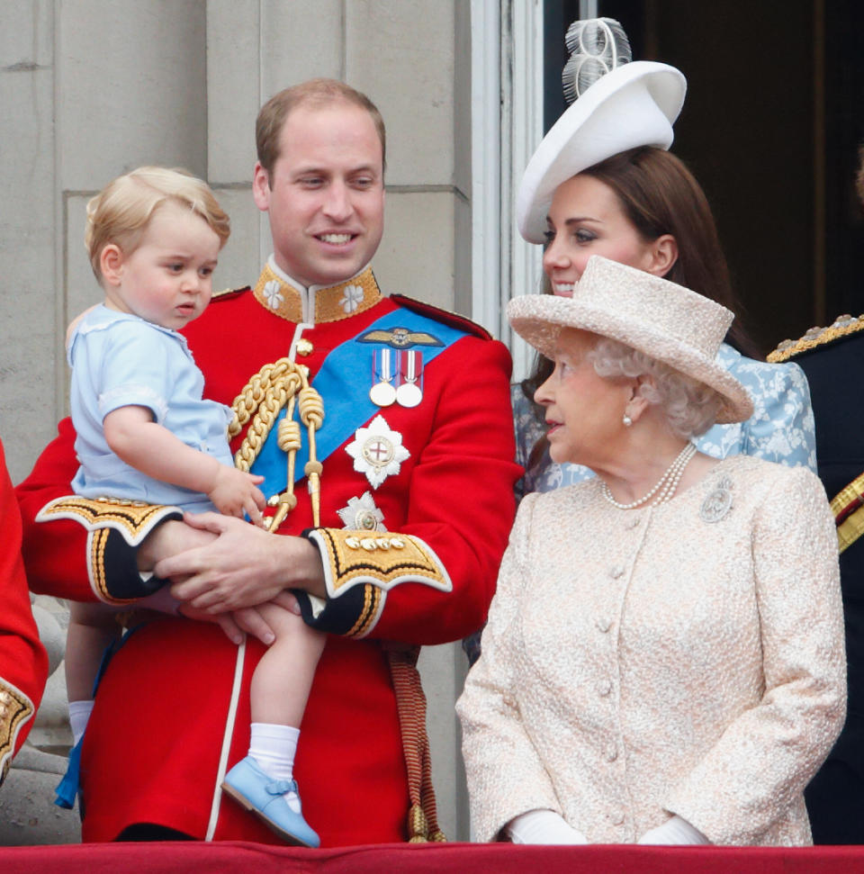 Prince William holds Prince George in his arms as the Queen and Kate Middleton look on on the Buckingham Palace balcony