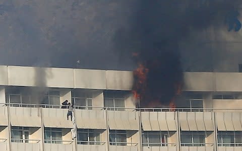 A man tries to escape from a balcony at Kabul's Intercontinental Hotel during an attack by gunmen  - Credit: Reuters