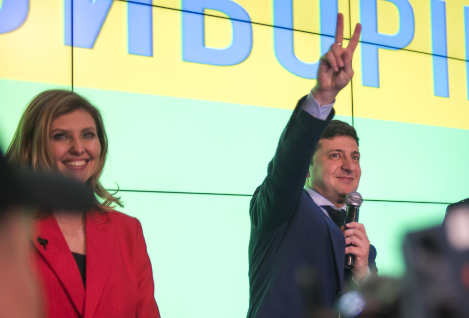 In this file photo taken on Sunday, March 31, 2019, Ukrainian comedian Volodymyr Zelenskiy, flashes the victory sign next to his wife Olena Zelenska, at the end of the presidential elections in Kiev, Ukraine. Zelenskiy took a commanding lead against the incumbent in Sunday’s presidential election, putting him in a strong position for the runoff in three weeks’ time, “This is only the first step toward a great victory,” Zelenskiy said after the vote. (AP Photo/Dan Braun, File)