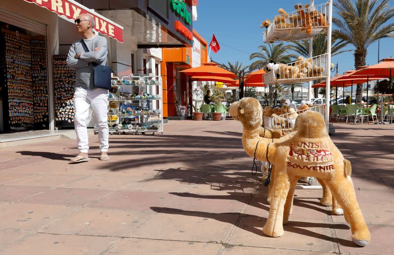 FILE PHOTO: A tourist walks past a souvenir shop in Hammamet