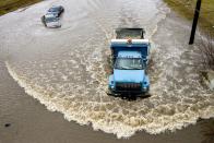 <p>A dirt truck plows through water, passing by two cars rendered unreachable by tow trucks after driving too deep into the the flooded street caused by heavy overnight rainfall on Wednesday, Feb. 21, 2018 in Flint, Mich. (Photo: Jake May/The Flint Journal-MLive.com via AP) </p>