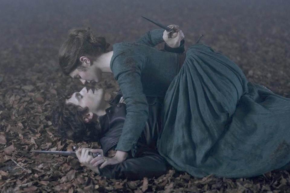 a still from my lady jane of jane grey on top of guildford dudley while both hold daggers behind their backs.