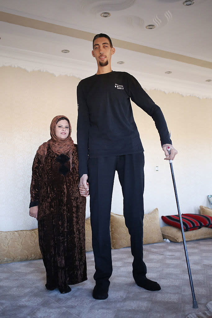 Sultan, with a can, holds hands with his wife, who is about half his height