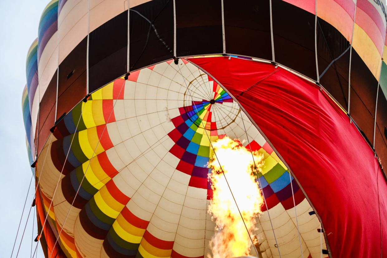 A low-angle shot of a hot-air balloon being inflated with a flaming burner.